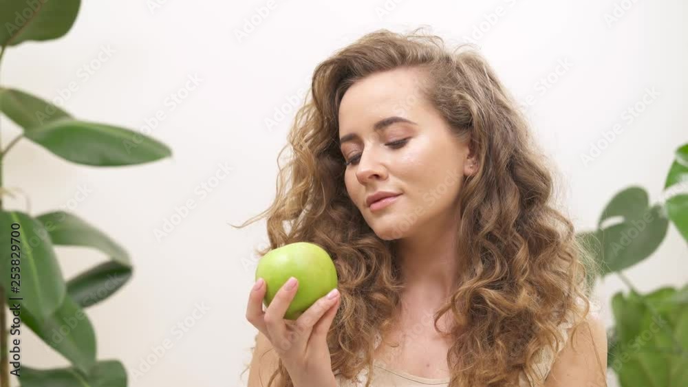 Beautiful young woman with gorgeous blond wavy hair holding green apple and smiling. Healthy lifestyle conception Beautiful young woman with gorgeous blond wavy hair holding green apple and smiling. Healthy lifestyle conception