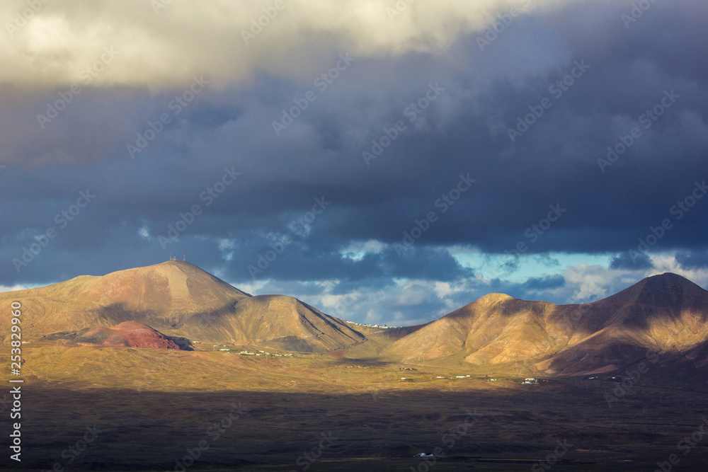 Beautiful view of the mountains of the South of Lanzarote island in the afternoon. Scattered white houses and clouds shadows.