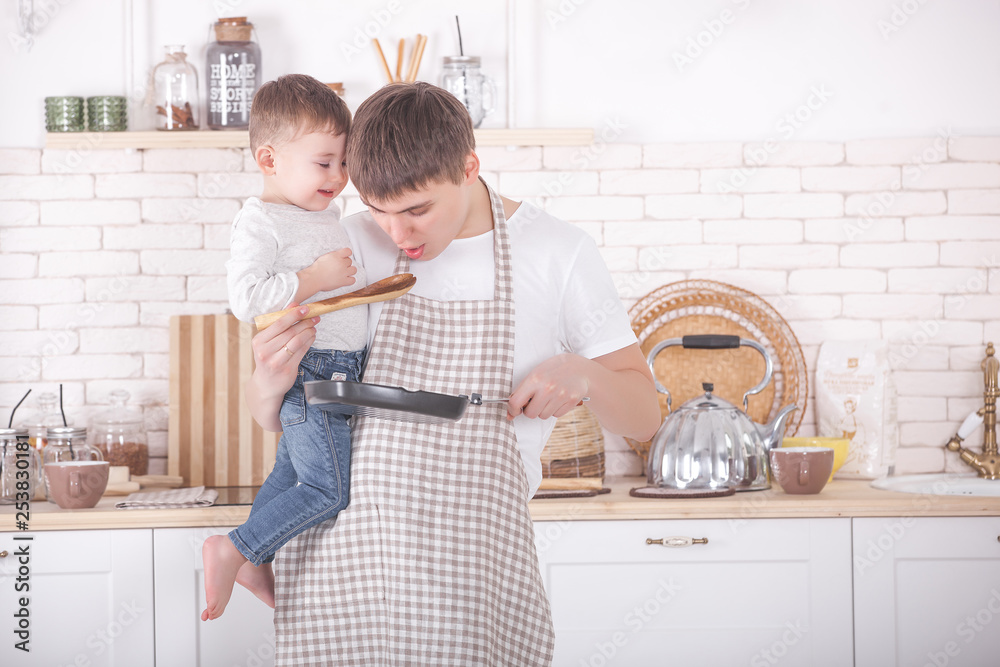 Young father cooking with his little baby on the kitchen. Dad and his son preparing breakfast. Little boy heps his father to cook. Stock Foto Adobe Stock
