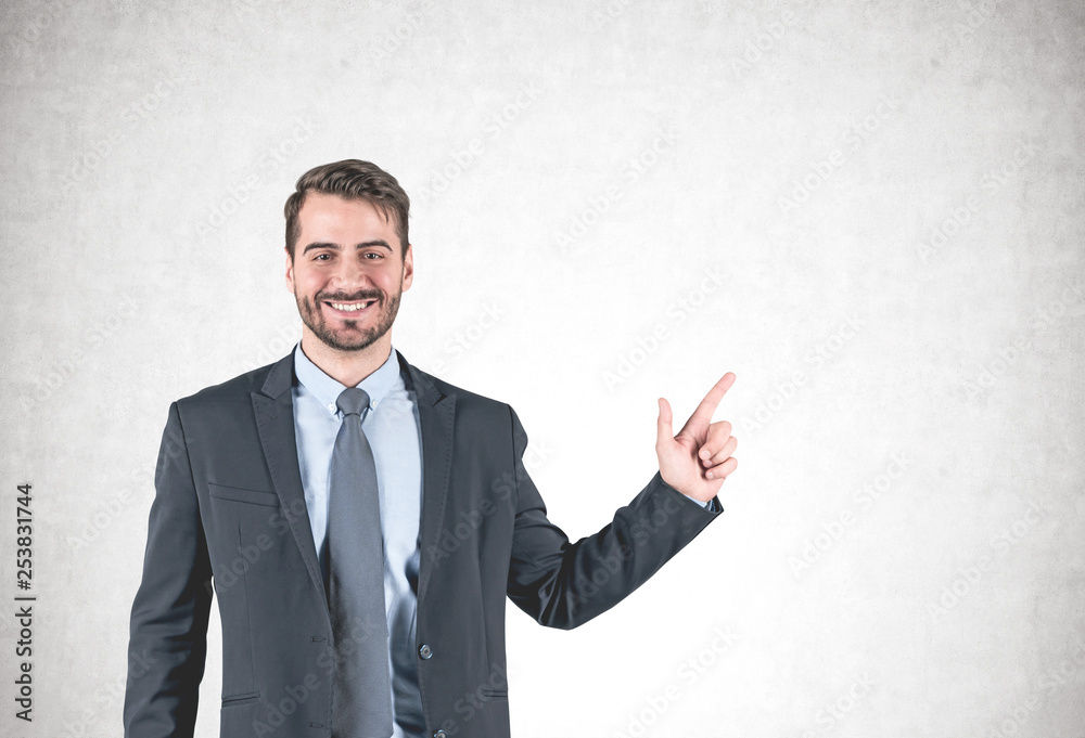 Smiling businessman pointing with finger, concrete Smiling businessman pointing with finger, concrete