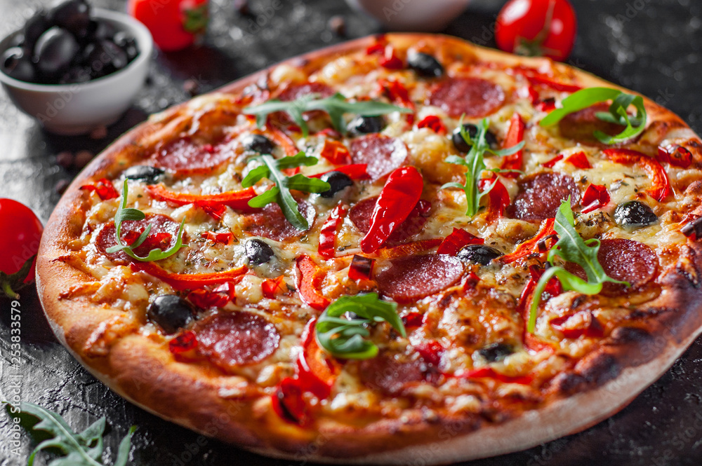 Pepperoni Pizza with Mozzarella cheese, salami, Tomatoes, olive, pepper, Spices and Fresh arugula. Italian pizza on dark background
