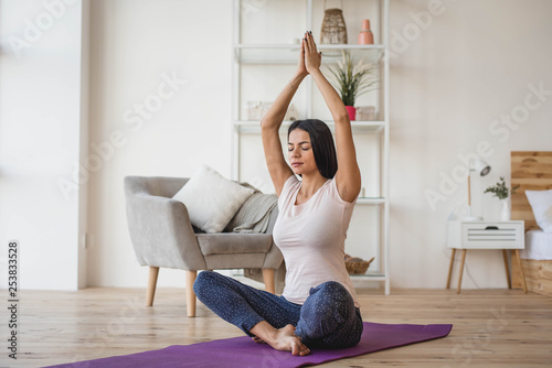 Young adult female doing yoga at home