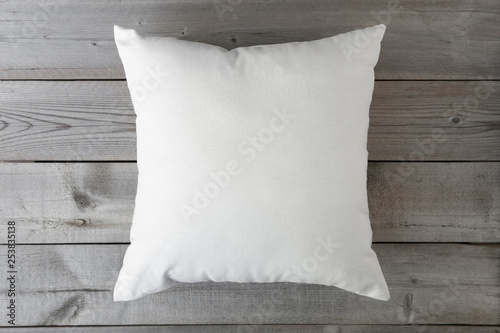 Flat lay mockup of white square cushion on a grey wooden background.