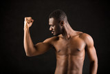 handsome african man on black background showing his muscles