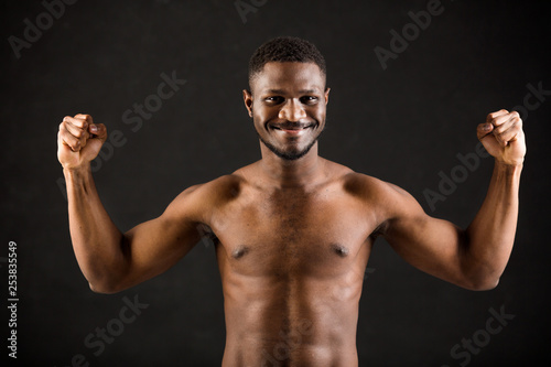 handsome african man on black background showing his muscles