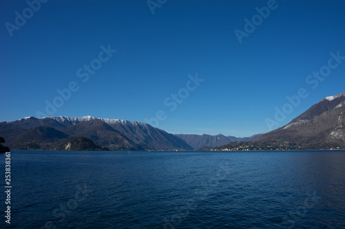 Italy, Menaggio, Lake Como, a large body of water with a mountain in the background © SkandaRamana