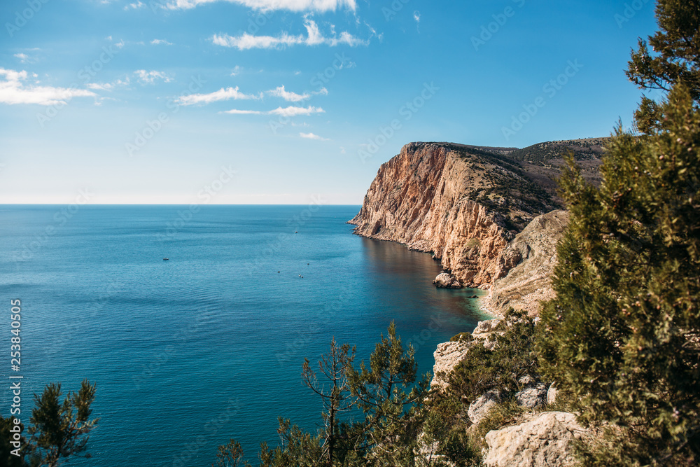 Beautiful Crimean rocky coast with high cliff and sea in sunny day, summer nature landscape for travel and rest