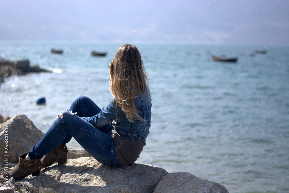 the melancholy girl in front of the lake, with boats moored