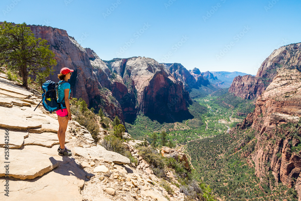 Young woman is looking at the magnificent view from Angel's landing in Zion National park. Travel and adventure concept.