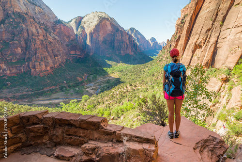 Young woman wearing backpack is looking at the view on the trail to Angel's Landing in Zion National park in Utah, USA. Female on a hiking trail in Zion National Park in Usa.