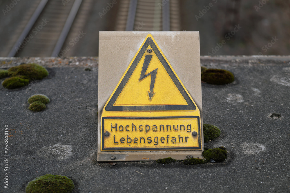 Warnschild Hochspannung Lebensgefahr an Bahnstrecke - Stockfoto Warnschild Hochspannung Lebensgefahr an Bahnstrecke - Stockfoto