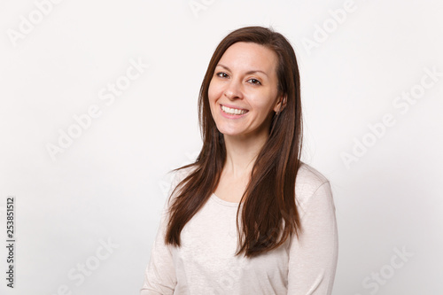 Portrait of smiling beautiful cute young woman in light clothes standing and looking camera isolated on white wall background in studio. People sincere emotions lifestyle concept. Mock up copy space.