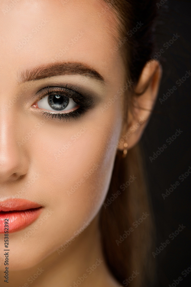 Portrait of a beautiful young girl with a clean face. A girl with a dark make-up on a dark background.