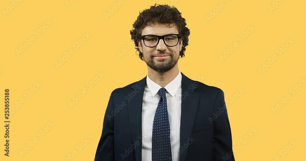 Close up of the cheerful Caucasian businessman in glasses, suit and tie doing gesture with hands like I don't know or whatever on the yellow background. Close up of the cheerful Caucasian businessman in glasses, suit and tie doing gesture with hands like I don't know or whatever on the yellow background.