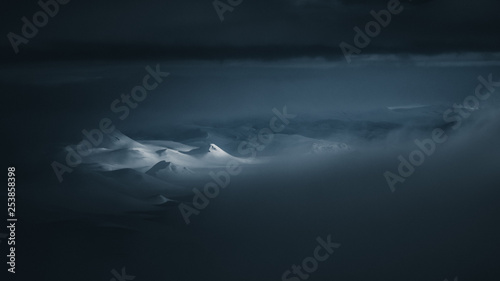 Snowy mountain peaks illuminated in a dark landscape