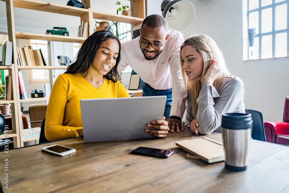 Confident business team having a meeting in loft office looking at tablet together Confident business team having a meeting in loft office looking at tablet together