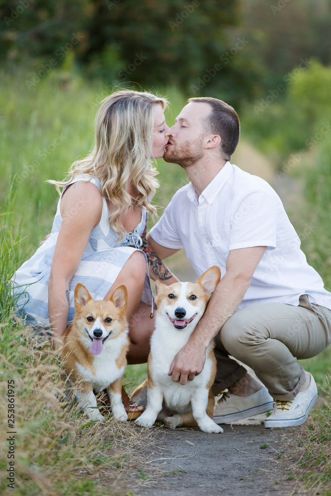 Couple kissing with corgi puppy and dog