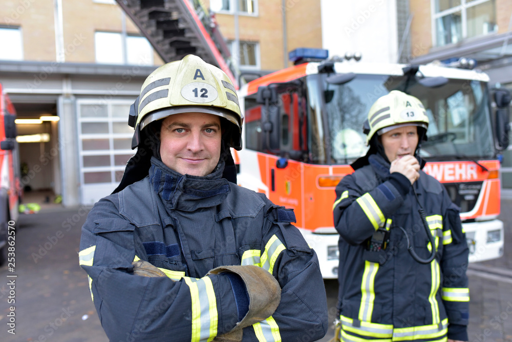 Portrait of two confident firefighters in front of fire engine Portrait of two confident firefighters in front of fire engine