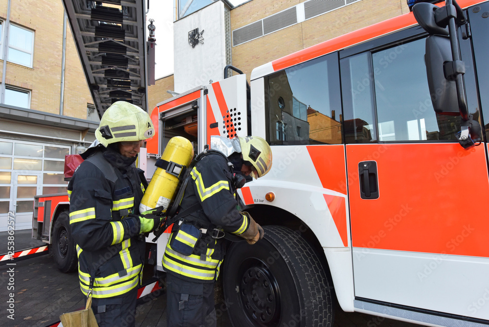 Two firefighters at fire engine preparing for an operation Two firefighters at fire engine preparing for an operation