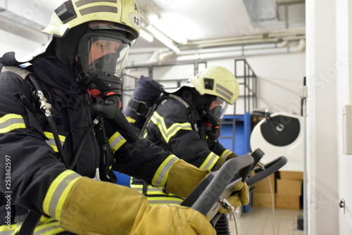 Two firefighters with respirator and air tank exercising on treadmill photo