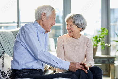 Senior couple sitting on couch talking together photo