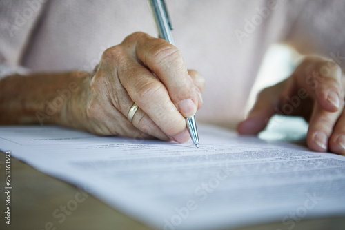 Senior woman's hand signing a document, close-up photo