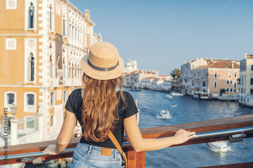 Fototapeta premium Woman in the Venice, standing on the bridge over the grand canal while on sightseeing in a foreign city. Discovery the Venice adventure.