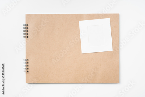 kraft notebook, photo frame and pen on white