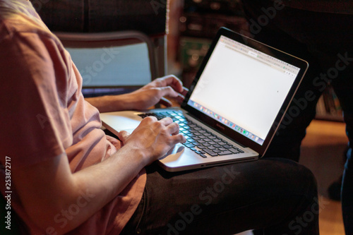 Fotografi man working with a laptop in his lap in a recording studio