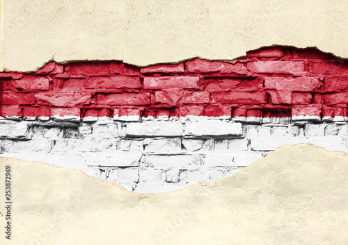 National flag of Indonesia on a brick background. Brick wall with partially destroyed plaster, background or texture.