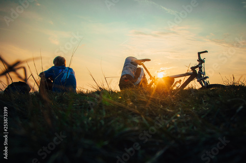 Man sitting by bicycle and watching sunset light