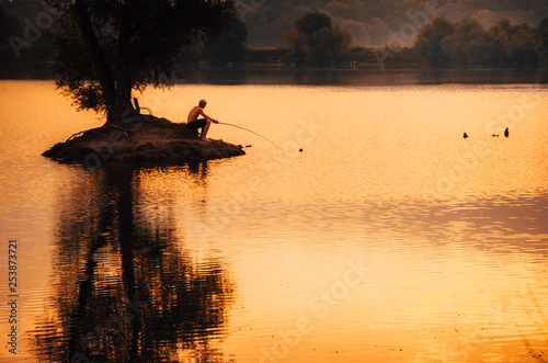 Alone fisherman on the small Iceland in the middle of lake. Loneliness, solitude, seclusion, singleness, separateness photo