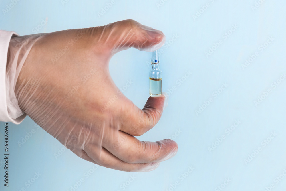 Male hand in a transparent medical nitrile glove holds a vial of medication. Medicine concept. Male hand in a transparent medical nitrile glove holds a vial of medication. Medicine concept.