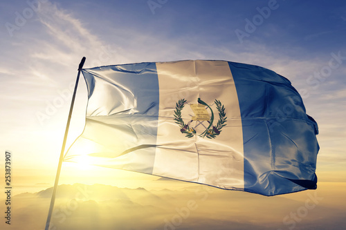 Guatemala flag waving on the top sunrise mist fog photo