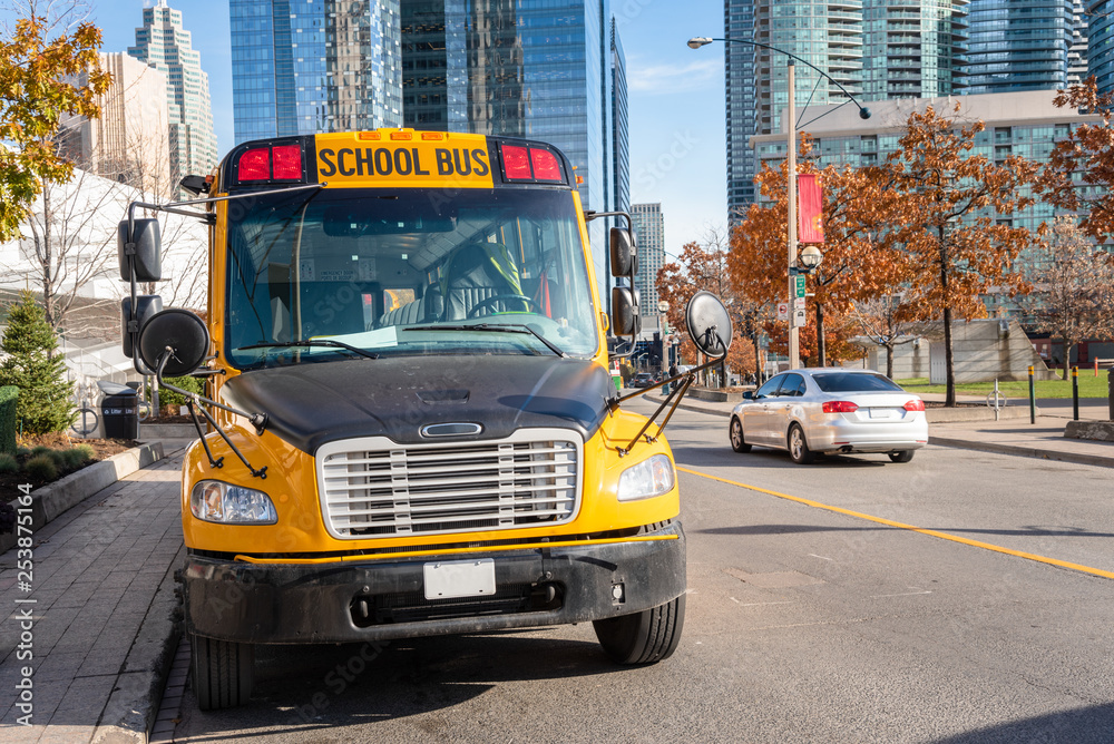 Fototapeta premium School Bus Parked along a Street in a City Centre on a Sunny Autumn Day