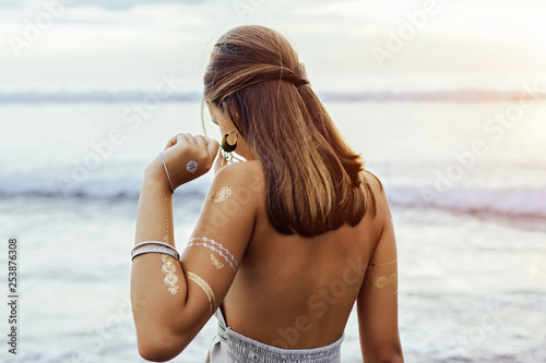 Young girl with silver tattoo and boho jewelry on sunset