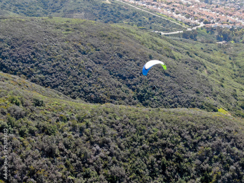 Para-glider over the top of the mountain during summer sunny day. Para-glider on the para-plane, strops -soaring flight moment flying over Black Mountain in San Diego, California. USA. photo