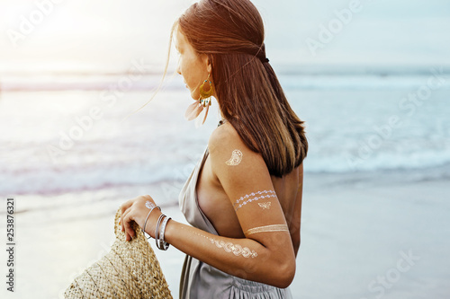 Young girl with silver tattoo and boho jewelry on sunset