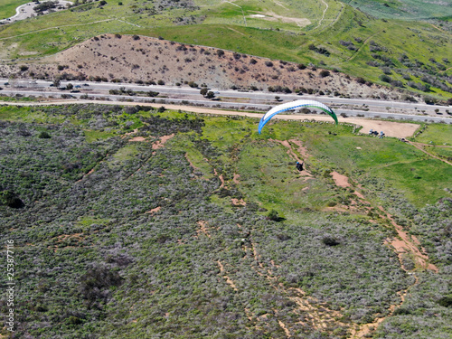 Para-glider over the top of the mountain during summer sunny day. Para-glider on the para-plane, strops -soaring flight moment flying over Black Mountain in San Diego, California. USA. photo