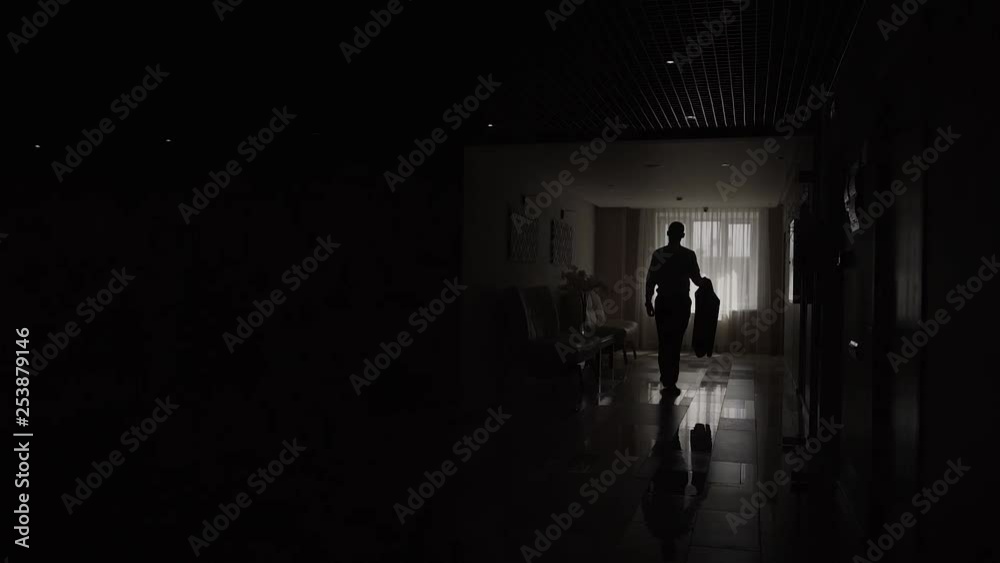 Man come to window, stay and look at large city apartment buildings outdoors, black figure against window, half length shot Man come to window, stay and look at large city apartment buildings outdoors, black figure against window, half length shot