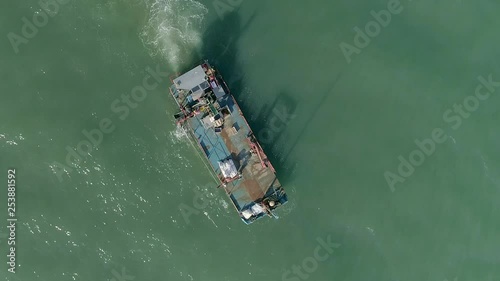 Top down aerial of a Shellfish mussel workboat with a conveyor belt moving around in the calm murky sea. photo