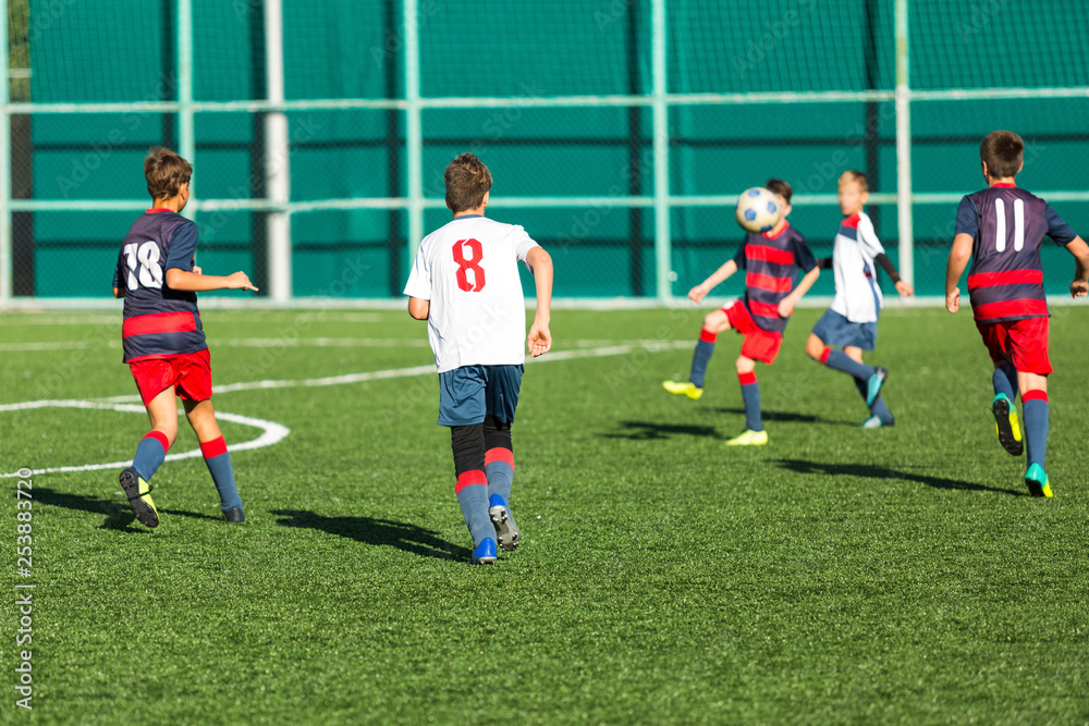 Obraz premium Football training soccer for kids. Boy runs kicks dribbles soccer balls. Young footballers dribble and kick football ball in game. Training, active lifestyle, sport, children activity concept