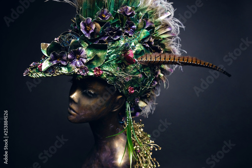 Studio shot of woman mannequin in creative headdress with feathers and flowers 