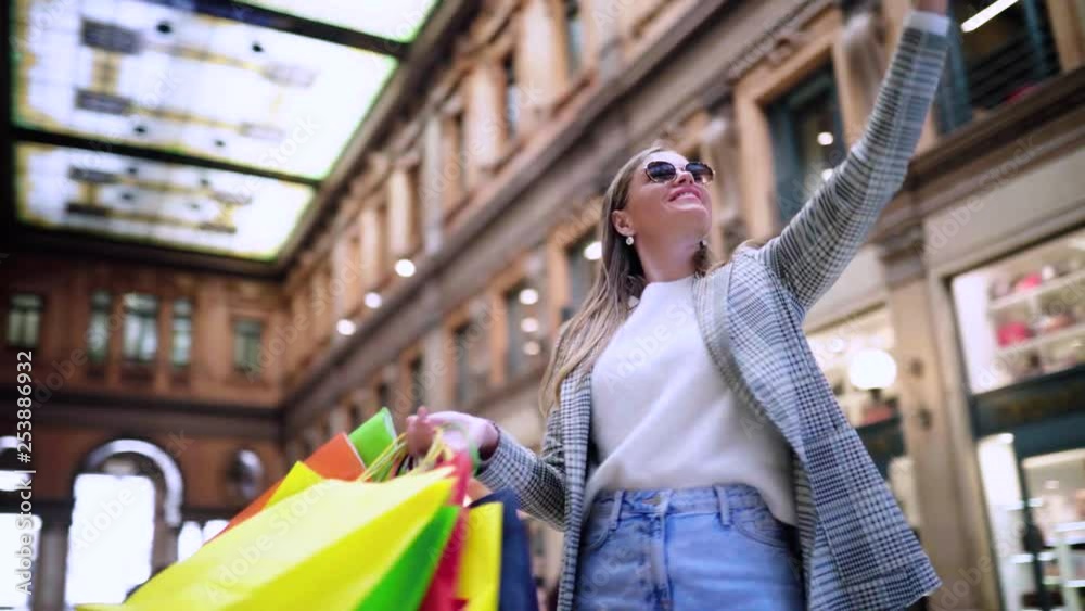 A happy tourist woman with shopping bags taking self-portrait picture with smartphone in the shopping mall in Europe. Concept: fashion, shopping, travel.