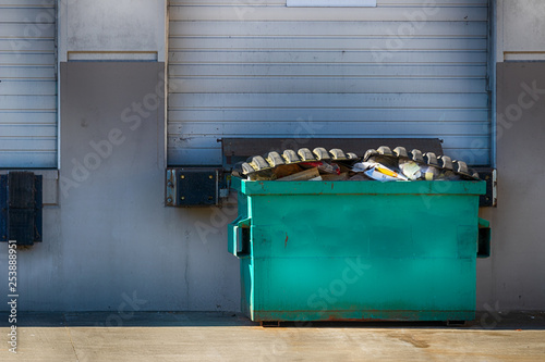 Warehouse exterior wall with garage door and dumpster photo