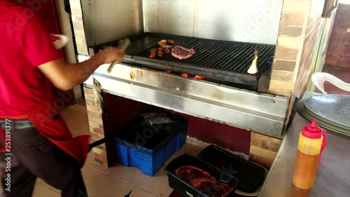 Chef In Red Apron Cooking Beef Meat On An Open Grill In A Restaurant In Mexico photo