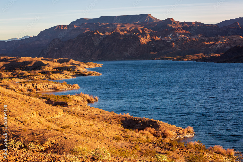 Lake Mead shore at sunrise with blue water and warm light