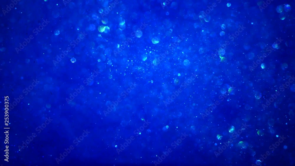 Abstract blue sparkly particle background with bokeh light and shiny frozen crystals in water LOOP.