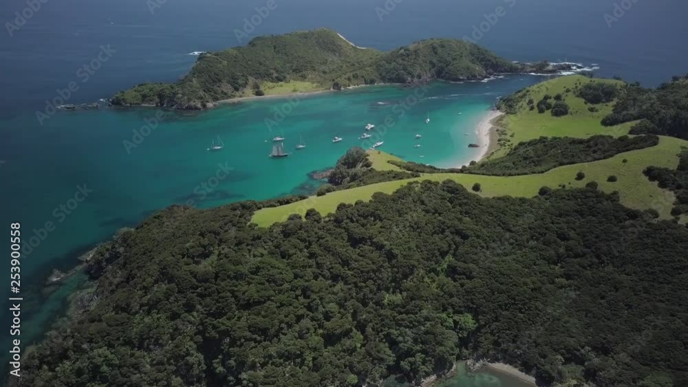 A top down aerial drone shot that depicts a fleet of anchored boats moored in a tropical paradise with a white sandy beach and crystal clear ocean waters. A top down aerial drone shot that depicts a fleet of anchored boats moored in a tropical paradise with a white sandy beach and crystal clear ocean waters.