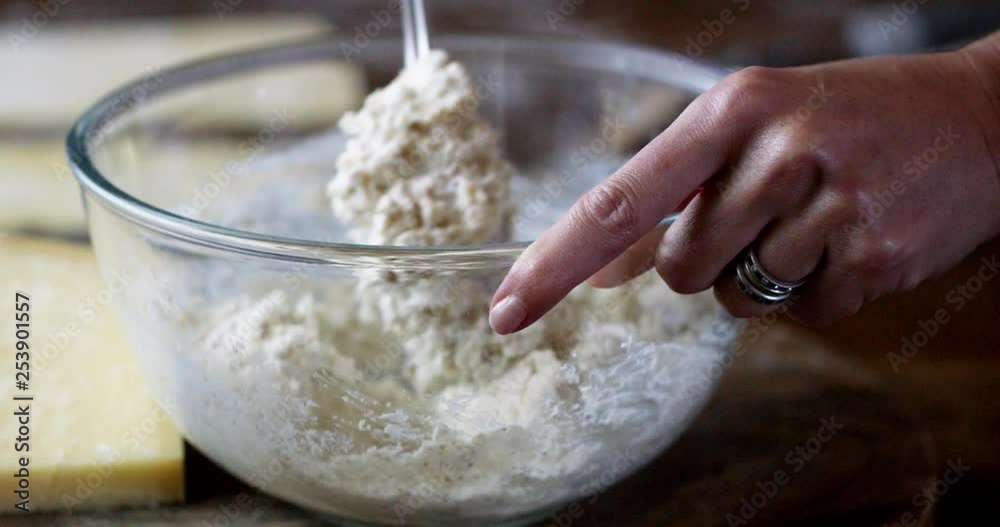 Slow motion shot of ricotta and chopped walnut ravioli filling ingredients being stirred together in a glass bowl. Side shot and you can see the hand stirring. Slow motion shot of ricotta and chopped walnut ravioli filling ingredients being stirred together in a glass bowl. Side shot and you can see the hand stirring.